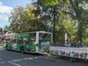 Heide-Shuttle Bus mit Fahrradanhänger, kostenloser Bus in der Lüneburger Heide, umgeben von Bäumen und einem Gebäude im Hintergrund